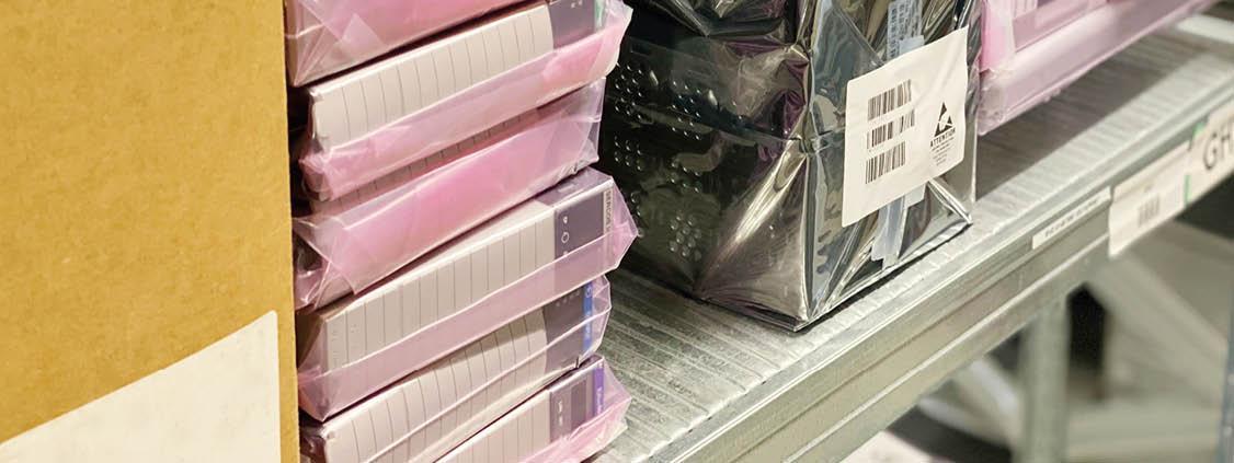 Industrial electronic components in protective packaging on a warehouse shelf.